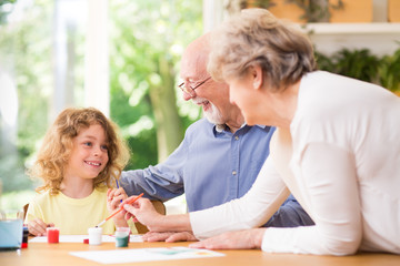 Grandparents painting a picture with paints with their grandson