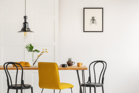 Stylish yellow chair at wooden dining table in trendy interior
