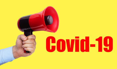 Hand holding megaphone and text covid-19 on yellow background.