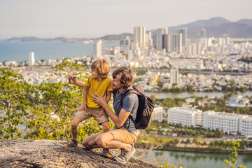Fototapeta na wymiar Dad and son tourists on the background of Nha Trang city. Travel to Vietnam with kids Concept