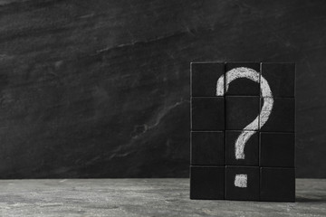 Wooden cubes with question mark on grey stone table. Space for text