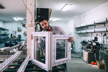 Aluminium and PVC industry worker making PVC or aluminium frames for windows and doors - obrazy, fototapety, plakaty