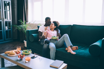 Young casual multiethnic couple passing time together at home