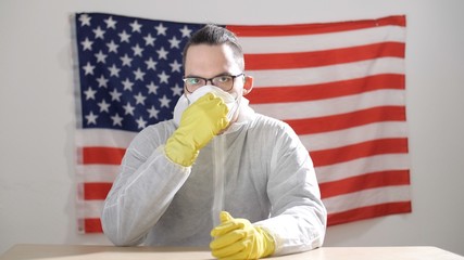 Man in protective suit putting or takes off on surgical mask for corona virus prevention. Man puts on a protective mask. Portrait of the man in protection mask. Epidemic situation. Novel coronavirus