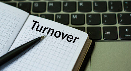 notebook with the word TURNOVER , on the background of a laptop
