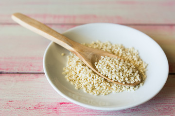 Closeup of sesame seeds in a wooden spoon.
