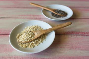 Various seeds in a wooden spoon on a wooden kitchen board.