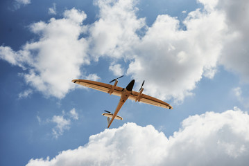 Modern small remote controlled white colored plane flying up in the sky