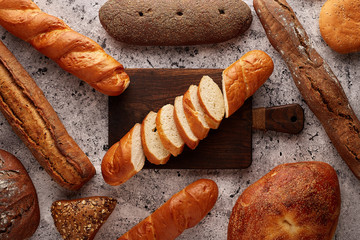 Sliced baguette on a cutting board on the concrete table.