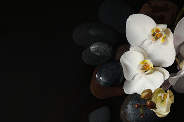 Fototapeta na wymiar Stones and orchid flowers in water on black background, flat lay with space for text. Zen lifestyle