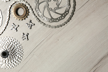Set of different bicycle parts on wooden background, flat lay. Space for text