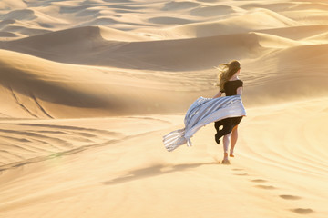 Caucasian young beautiful girl alone is in a hot, waterless desert Runs along the sandy mountains and dunes.