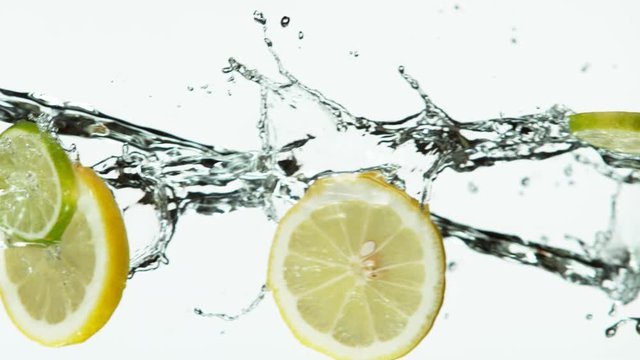 Super slow motion of lime and lemon slices with water splash on white background. Filmed on high speed cinema camera, 1000 fps.