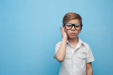 Funny little caucasian boy in glasses on a blue background.
