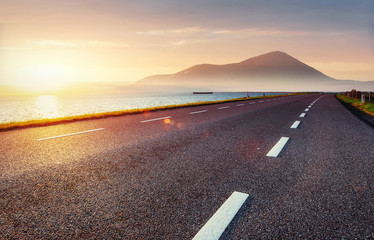 Asphalt road along the sea at sunset - Powered by Adobe