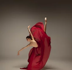 Tuinposter Passioned in motion. Graceful classic ballerina dancing on grey studio background. Deep red cloth. The grace, artist, movement, action and motion concept. Looks weightless, flexible. Fashion, style. © master1305