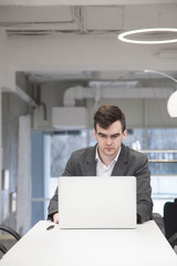 young businessman works in an office with a laptop