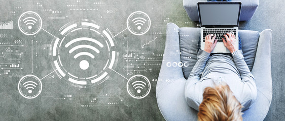 Wifi theme with man using a laptop in a modern gray chair