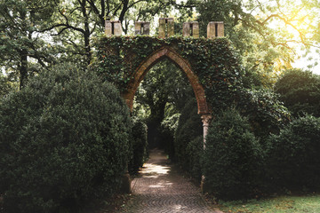 Ancient stone portal covered with leaves leading to the secret garden