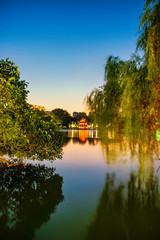 Obraz premium Turtle Tower in the center of Hoan Kiem Lake(Lake of the Returned Sword) framed by trees. This tower is a popular tourist attraction in Hanoi, Vietnam