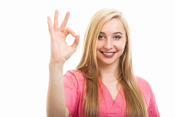 Fototapeta premium Portrait of young female nurse wearing scrubs showing ok gesture