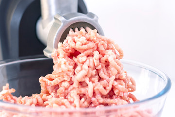 Closeup of minced meat exiting from a grinder. Healthy homemade stuffing. on a light background