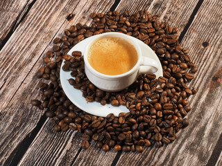 Coffee cup with coffee beans on wooden background.