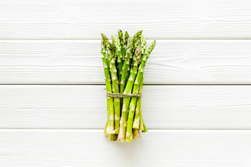 Bunch of asparagus steams on white wooden background top-down copy space