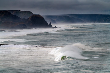 Scenic view of the coastline along the Amado Beach (Praia do Amado) with big waves during a storm, in Algarve, Portugal