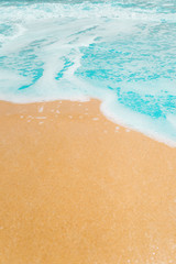 Fototapeta na wymiar Soft waves with foam blue ocean sea on golden sand with copy space.