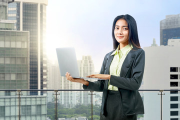 Asian businesswoman standing while using a laptop
