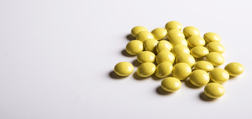 Yellow Pills on a white plate. Isolated on white background. Copy space.