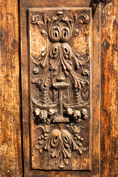Vertical picture of traditional carved decoration on wooden entrance door. Carved wooden elements in Provence, France. Authentic local provencal building decor. Details of a fine wood carving art.