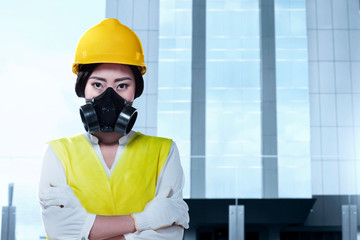 Asian worker woman with a protective mask and yellow helmet standing