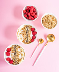Yogurt with granola, chia seed, raspberry and banana, healthy breakfast concept, pastel pink background, top view
