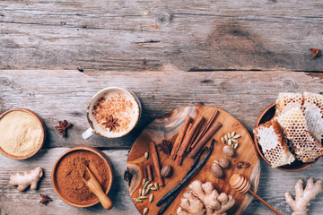 Tea with milk, cloves, ginger, cardamom, cinnamon, anise, vanile, honey, nutmeg. Indian masala tea with spices. Top view, copy space. Antiviral beverage. Healthy ayurvedic spice drink chai