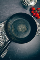 Empty cast iron frying pan on dark grey culinary background, view from above
