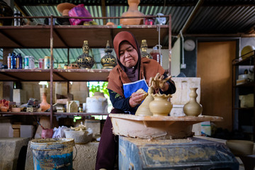 Local woman demonstrates on making traditional clay jar called 