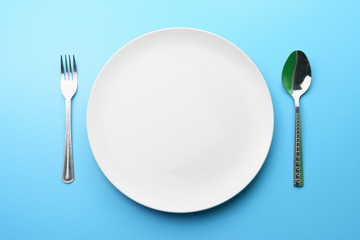 dieting and health care concept. top view the white plate with fork and spoon on blue dine table. flat lay. free copy space for your text