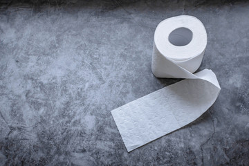 Roll of white soft toilet paper on dark background. Personal hygiene concept. Flat lay, top view.