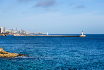 Fototapeta premium View of the old Saint Elmo Lighthouse, Valletta,Malta,Mediterranean Sea,Light tower.St Elmo Bridge or Breakwater Bridge,single-span arched truss steel sea footbridge in Valletta, Malta.Valletta bridge
