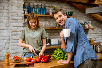 Young  woman cooking while man drinking coffee