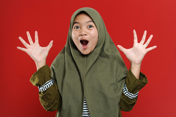 Portrait of excited young Muslim woman with hijab, keeping mouth open, spreading hands, People Surprised