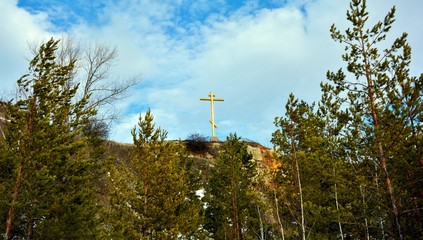 Obraz premium Golden cross on top of a mountain against a bright blue sky