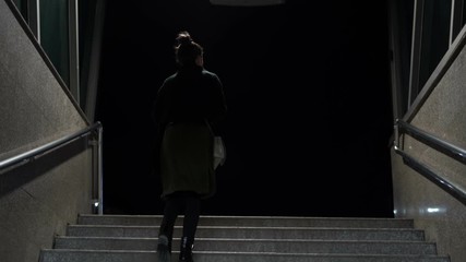 Woman walking the subway staircase alone at night. Horror, kidnap concept