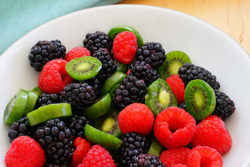 Bowl of fresh sliced baby kiwi fruit, raspberries and blackberries