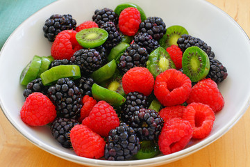 Bowl of fresh sliced baby kiwi fruit, raspberries and blackberries