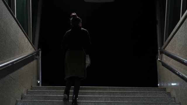 Woman walking the subway staircase alone at night. Horror, kidnap concept