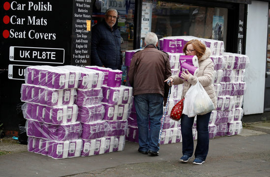 People buy toilet rolls on sale outside a car parts shop in Manchester, as the number of coronavirus cases grow around the world