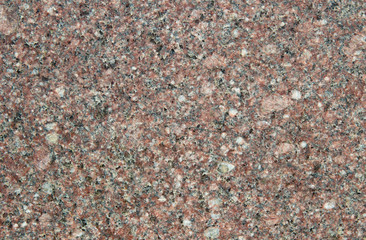 The texture of the pale pink slice of granite with small black, white and transparent blotches. Mica, spar and quartz on a stone cut
